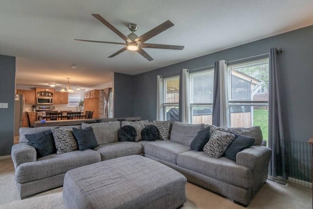 living area featuring light carpet and ceiling fan with notable chandelier