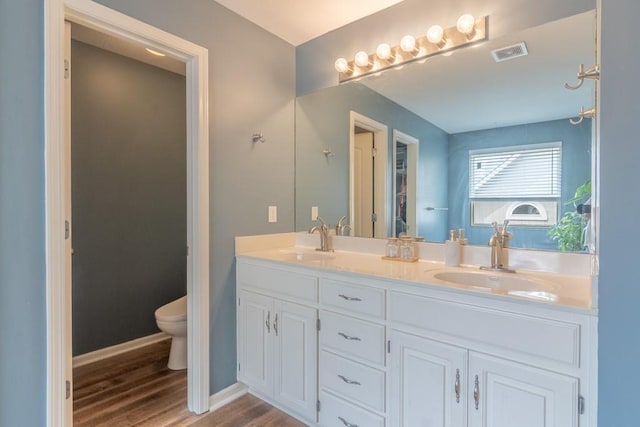 full bathroom with toilet, visible vents, a sink, and wood finished floors