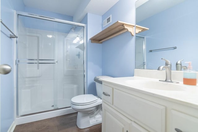 full bath featuring vanity, toilet, wood finished floors, visible vents, and a stall shower