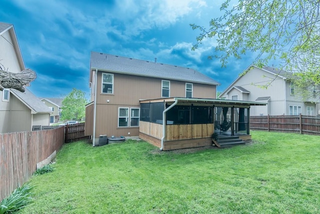 rear view of house with a yard, a fenced backyard, and a sunroom