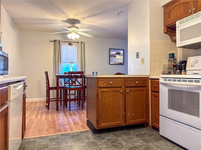 kitchen with white appliances, ceiling fan, light countertops, brown cabinets, and backsplash