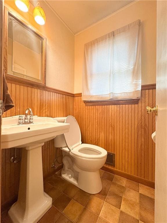 bathroom featuring wooden walls, toilet, and a wainscoted wall