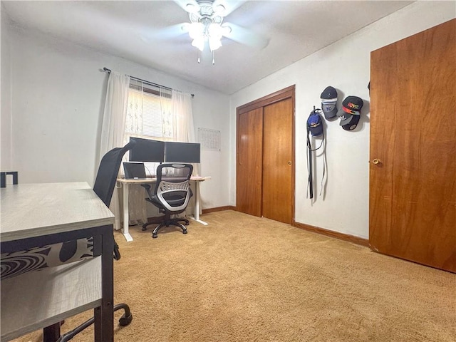 carpeted office space featuring baseboards and a ceiling fan