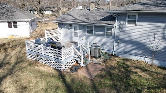 rear view of house with a deck, a lawn, a shingled roof, and central AC