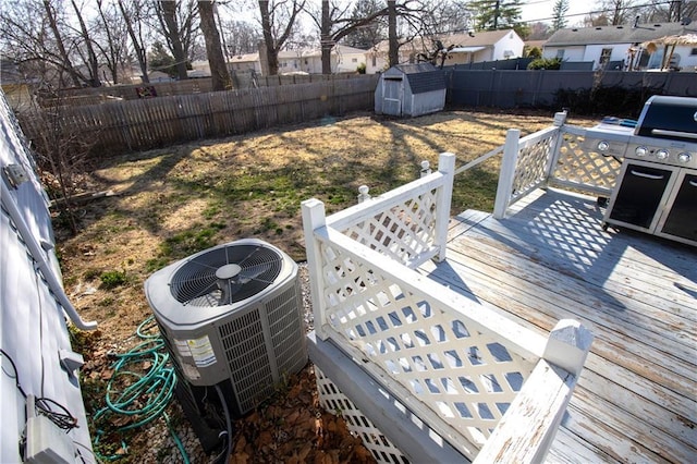 wooden terrace with an outbuilding, central air condition unit, a storage unit, and a fenced backyard