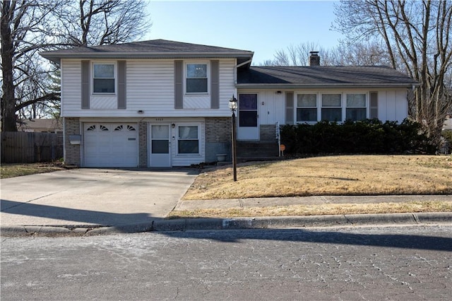 tri-level home with fence, an attached garage, a chimney, concrete driveway, and brick siding