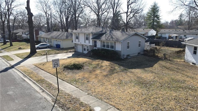 split level home with a residential view, concrete driveway, and fence