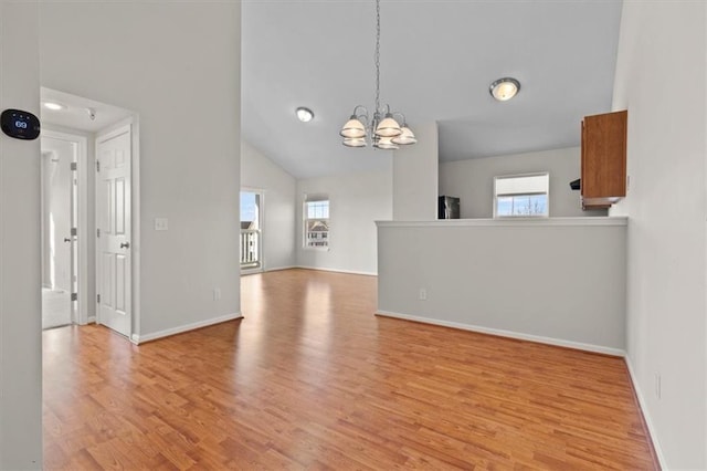 5501 NE 80th Ter Unit 3A, Kansas City, MO 64119 - unfurnished living room with an inviting chandelier, baseboards, light wood-style flooring, and lofted ceiling