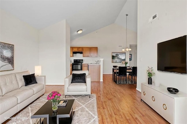 5501 NE 80th Ter Unit 3A, Kansas City, MO 64119 - living area with high vaulted ceiling, a notable chandelier, light wood-style flooring, and visible vents