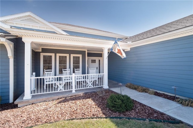 entrance to property featuring roof with shingles and a porch