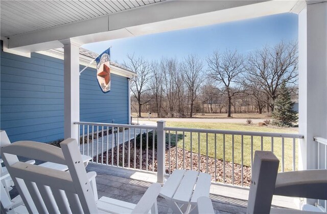 wooden terrace with a lawn and covered porch