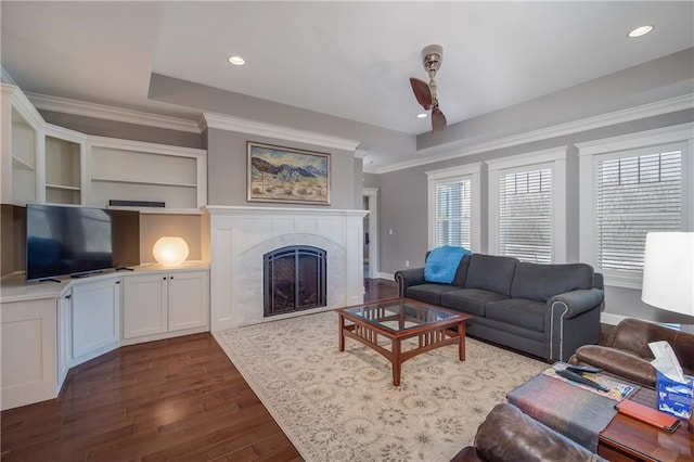 living area with dark wood-style floors, recessed lighting, a tiled fireplace, and crown molding