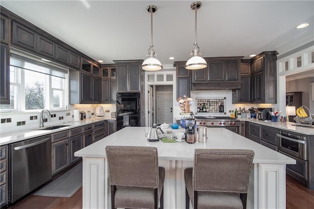 kitchen with a sink, a kitchen breakfast bar, a center island, stainless steel appliances, and decorative backsplash