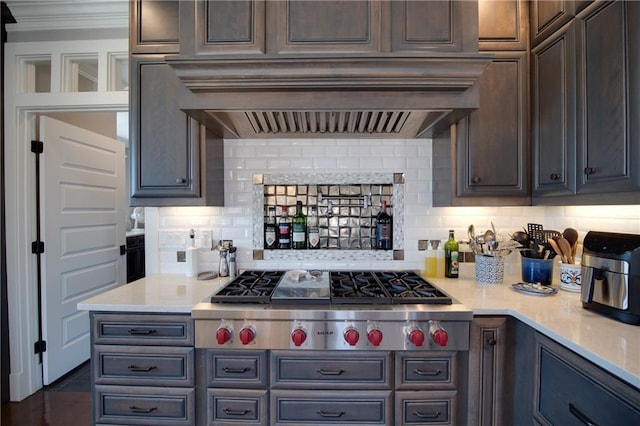 kitchen with tasteful backsplash, crown molding, premium range hood, stainless steel gas cooktop, and light countertops