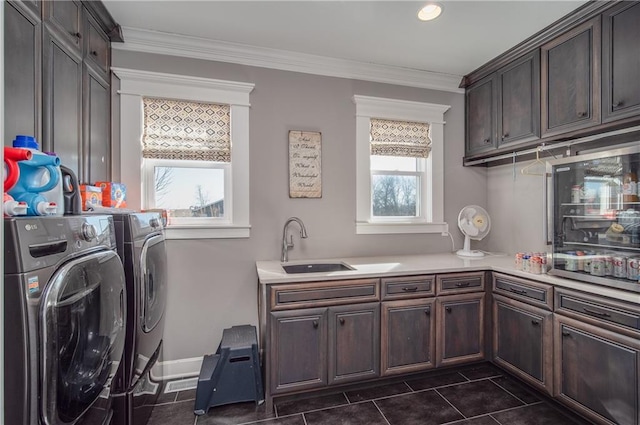 clothes washing area featuring cabinet space, crown molding, washing machine and dryer, and a sink