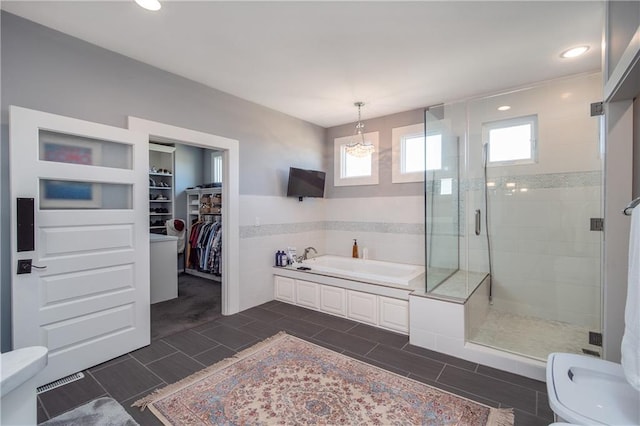 bathroom featuring toilet, a spacious closet, a bath, and a shower stall