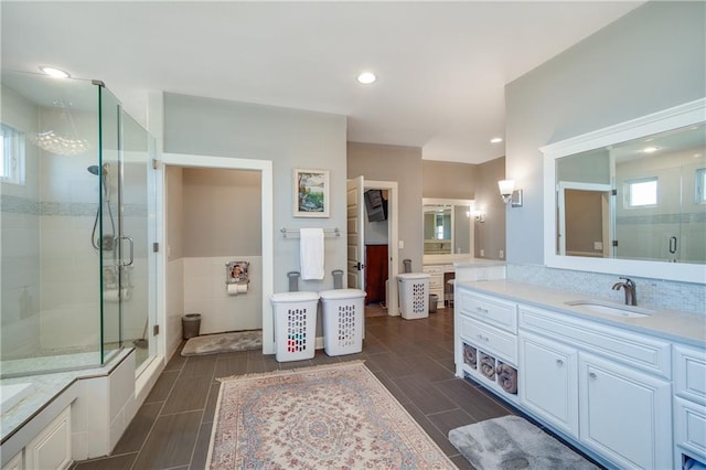 bathroom with plenty of natural light, a shower stall, two vanities, and a sink