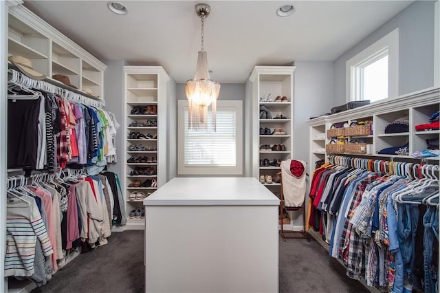 spacious closet featuring dark carpet and an inviting chandelier