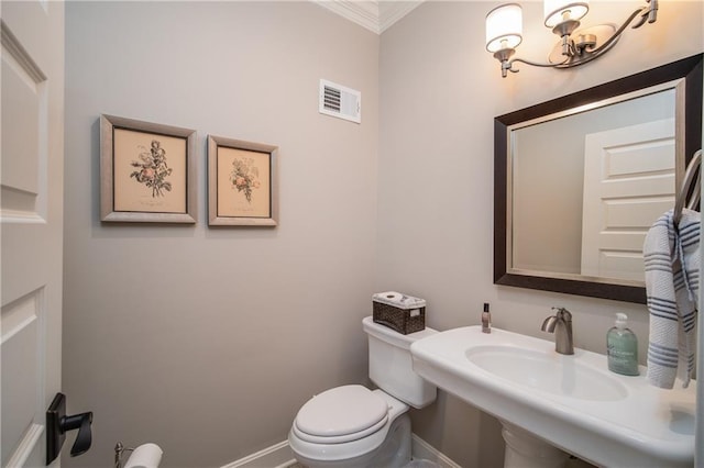 half bath with visible vents, crown molding, baseboards, toilet, and a sink