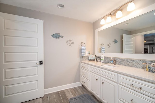 bathroom featuring tasteful backsplash, vanity, baseboards, and wood finished floors