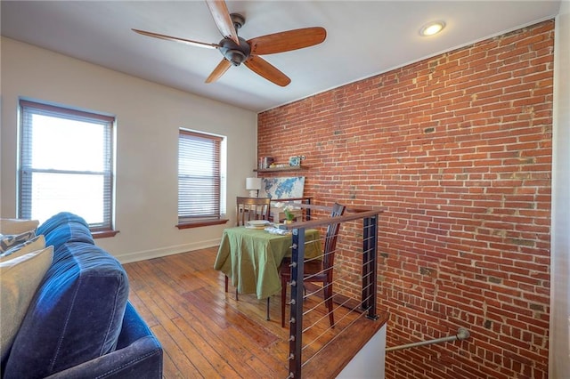 interior space featuring hardwood / wood-style floors, baseboards, and brick wall