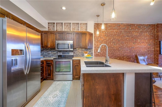 kitchen with backsplash, appliances with stainless steel finishes, a peninsula, light wood-style floors, and a sink