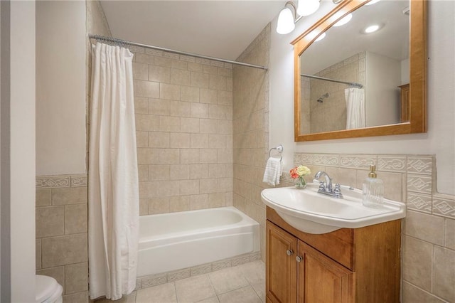 bathroom featuring tile patterned floors, shower / bathtub combination with curtain, toilet, tile walls, and vanity