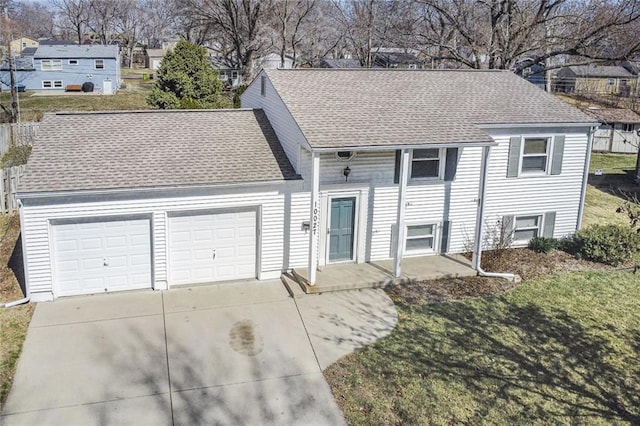 split foyer home with fence, driveway, roof with shingles, a front lawn, and a garage