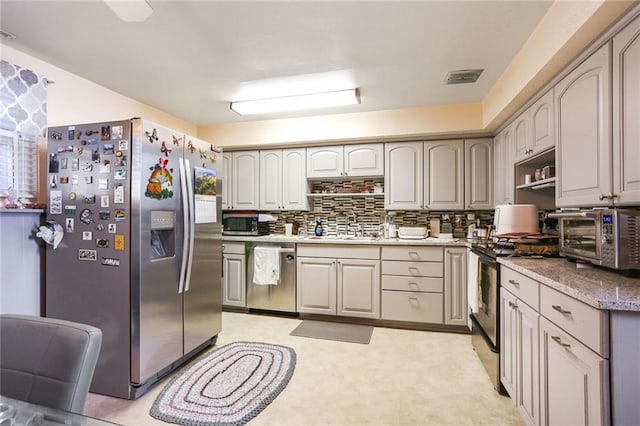 kitchen featuring visible vents, a sink, backsplash, appliances with stainless steel finishes, and a toaster