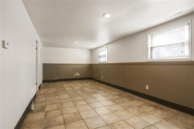 empty room featuring wooden walls, recessed lighting, visible vents, and a wainscoted wall