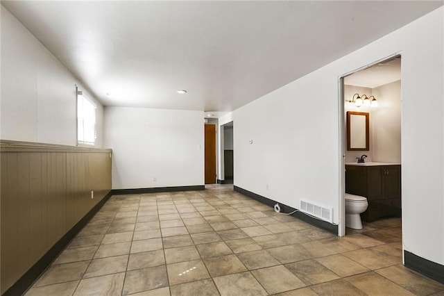 empty room with tile patterned flooring, baseboards, visible vents, and a sink