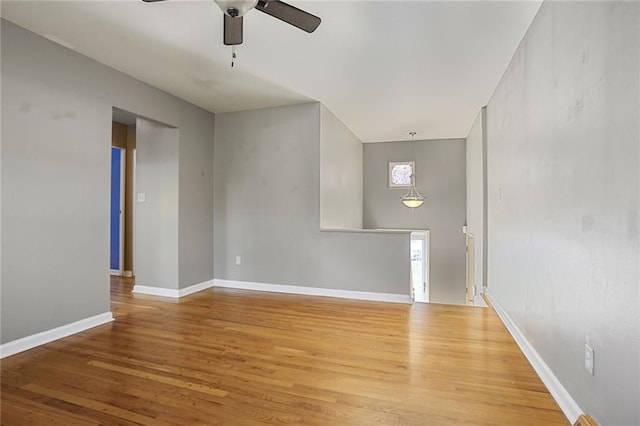 empty room with baseboards, a ceiling fan, and wood finished floors