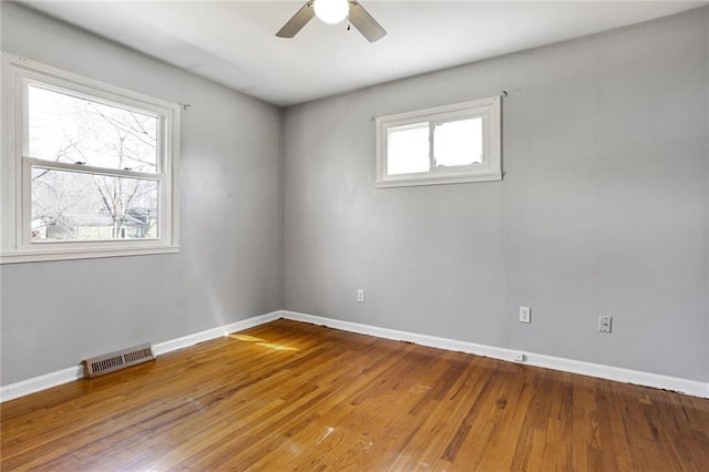 empty room with visible vents, baseboards, ceiling fan, and wood finished floors