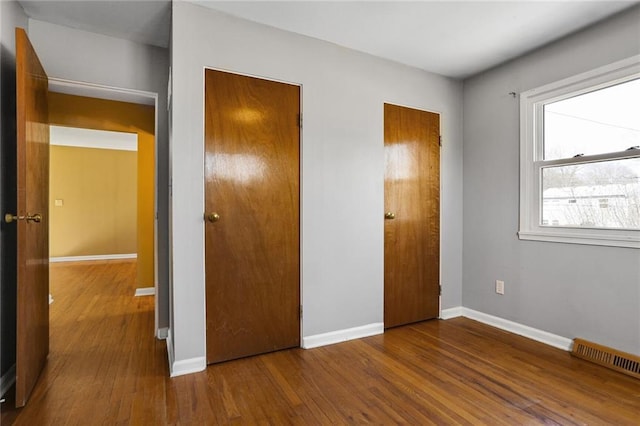 unfurnished bedroom featuring wood finished floors, visible vents, and baseboards