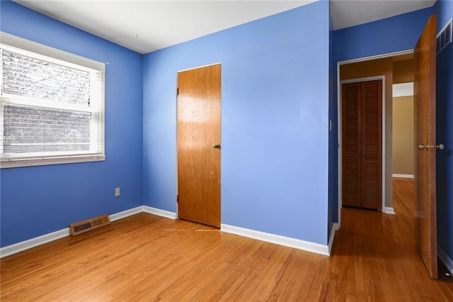 unfurnished bedroom featuring wood finished floors, visible vents, and baseboards