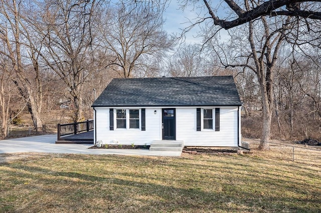 view of front of house with a front lawn, fence, and a shingled roof