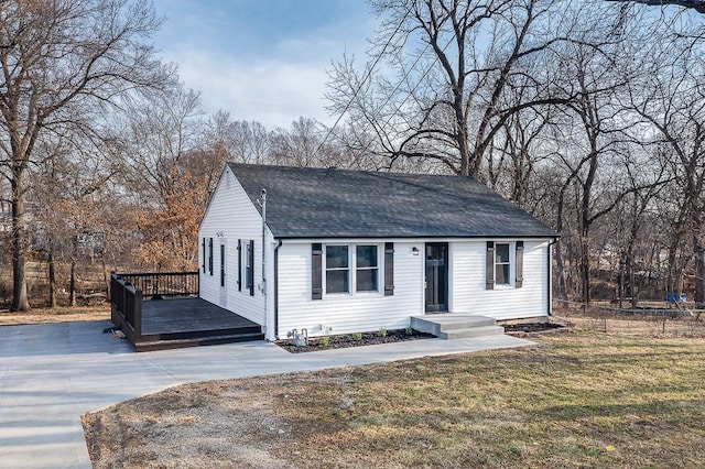 view of front of house with a front yard, fence, roof with shingles, and a wooden deck