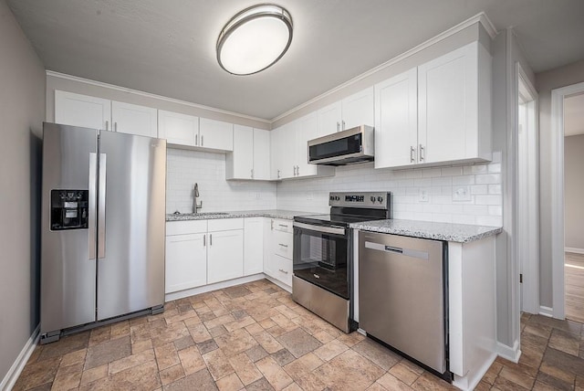 kitchen with stone tile flooring, white cabinets, appliances with stainless steel finishes, and a sink