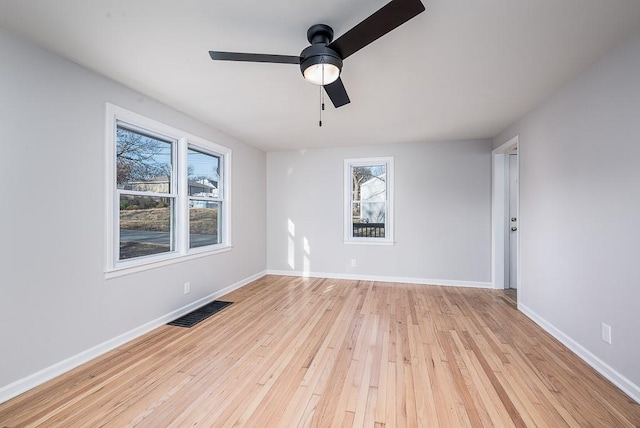 empty room featuring visible vents, light wood-style flooring, baseboards, and a healthy amount of sunlight