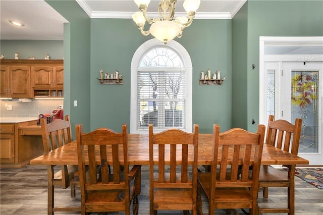 dining room with an inviting chandelier, wood finished floors, and ornamental molding