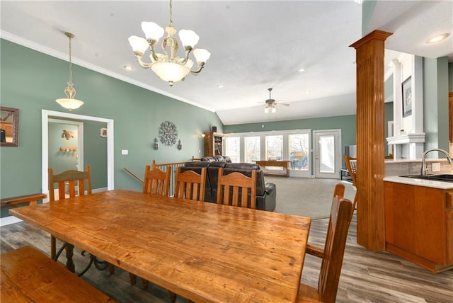 dining area with ceiling fan with notable chandelier, wood finished floors, crown molding, decorative columns, and vaulted ceiling