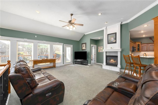 living room with a ceiling fan, baseboards, crown molding, light colored carpet, and a large fireplace