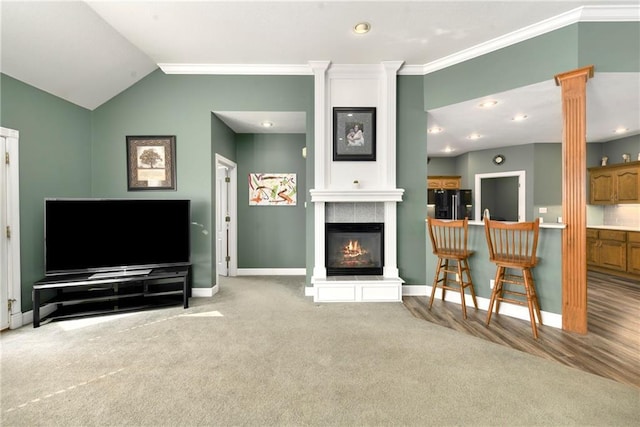 living room with baseboards, a large fireplace, crown molding, decorative columns, and lofted ceiling