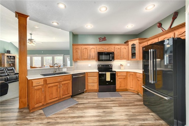 kitchen with black appliances, glass insert cabinets, backsplash, and a sink