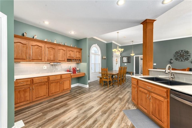 kitchen with tasteful backsplash, light wood finished floors, a sink, brown cabinets, and stainless steel dishwasher