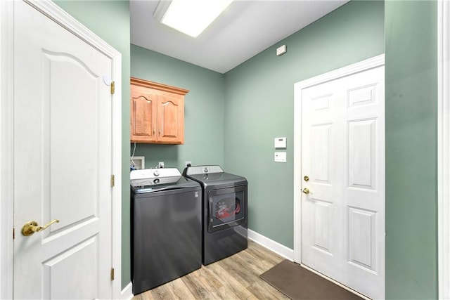 laundry room with baseboards, cabinet space, separate washer and dryer, and light wood-style flooring