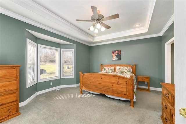 carpeted bedroom with a raised ceiling, crown molding, baseboards, and ceiling fan