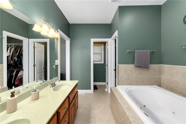 bathroom with baseboards, double vanity, a whirlpool tub, a sink, and a walk in closet