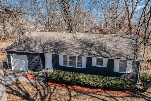 view of front of home with a shingled roof, entry steps, a chimney, a garage, and driveway