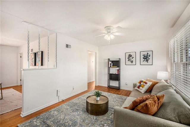 living room with wood finished floors, visible vents, and baseboards